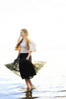 Creative Highlights Symbolbilder A young woman with curly hair walking in shallow water while ho United States, Florida, Crystal River R_YWQX2406196E-1463628-01 ,model released, Symbolfoto