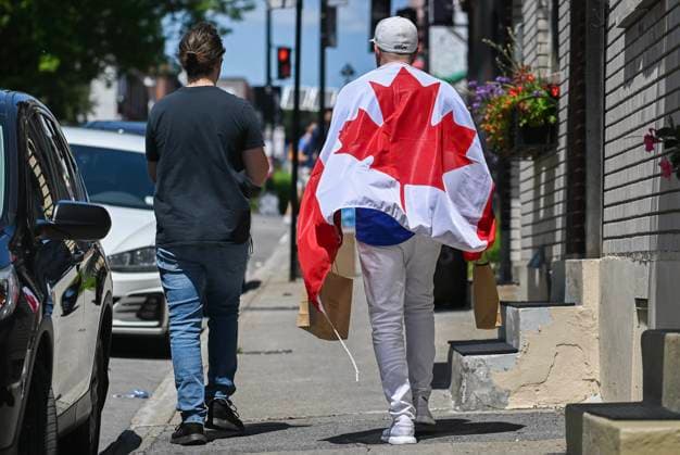 July 1, 2024, Montreal, Pq, Canada: A man wears a Canadian flag as he walks along a street on Canada Day in Montreal, Monday, July 1, 2024. Montreal Canada  - ZUMAc35_ 20240701_zaf_c35_027 Copyright: xGrahamxHughesx