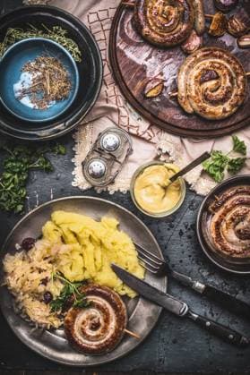 Roasted sausage with Mashed Potatoes and pickled cabbage served on dark rustic table with mustard, top view. German traditional food ,model released, Symbolfoto