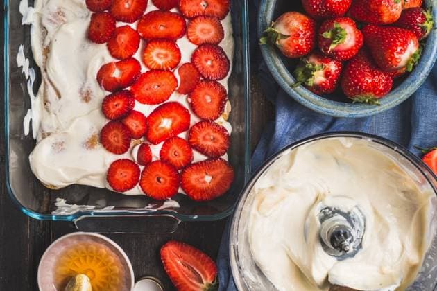 Strawberry dessert making. Dish with sliced berries and cream on dark rustic background, top view ,model released, Symbolfoto