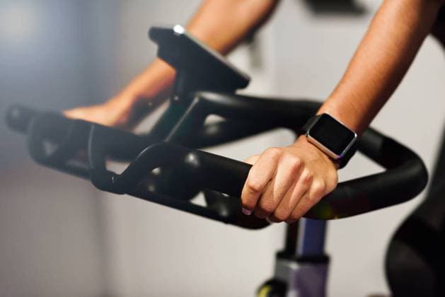 Hands of a woman training at a gym doing spinning or cyclo indoor with smart watch. Sports and fitness concept. ,model released, Symbolfoto