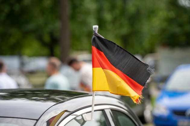 Munich, Bavaria, Germany - July 5, 2024: Germany flags on a window of a car or passenger car, in front of the parking lot of a fan zone for the European Championship soccer match of the German national team.