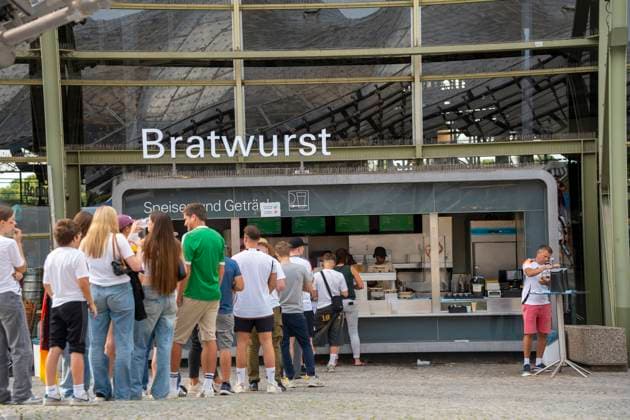 Munich, Bavaria, Germany - July 5, 2024: Munich fan zone for the UEFA Euro 2024 European Championship at the public viewing. People and fans are queuing to get beer (drinks) and bratwurst (food).