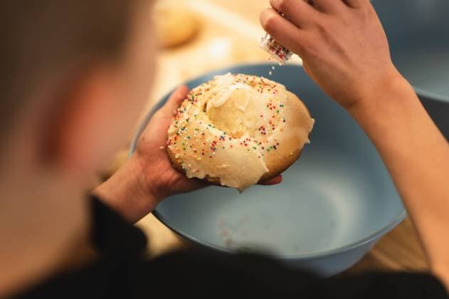 Overhead view of child shaking sprinkles on Easter egg basket cookies Chicago, Illinois, United States R_AKAO240707-1467014-01