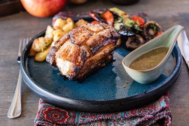Roast pork loin glazed with a rich honey sauce, accompanied by a colorful salad of grilled vegetables and potatoes, served on a blue ceramic plate with a rustic setting Model Released AnnaBogush_ID22685_661225_002 Copyright: xAnnaxBogushx
