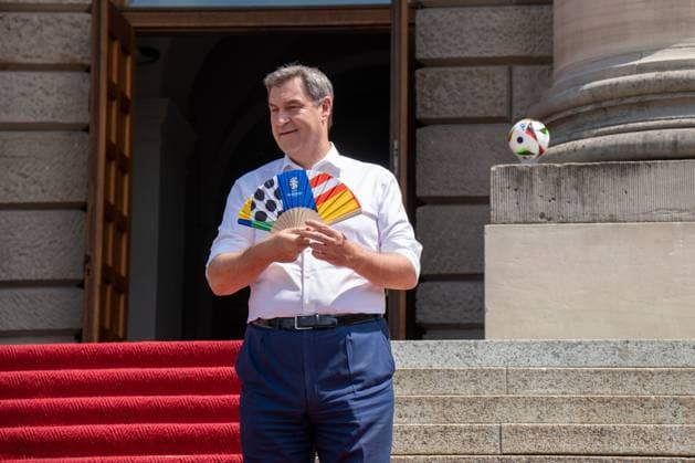 Munich, Bavaria, Germany - 11 July 2024: Prime Minister of Bavaria Dr. Markus Söder honoring the volunteers of the European Championship. He is hot and cools himself with a UEFA fan
