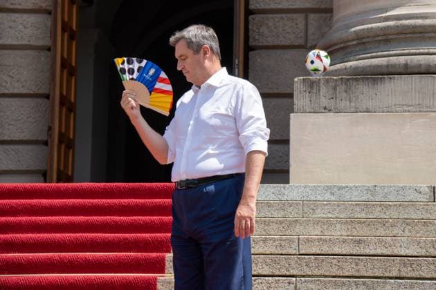 Munich, Bavaria, Germany - 11 July 2024: Prime Minister of Bavaria Dr. Markus Söder honoring the volunteers of the European Championship. He is hot and cools himself with a UEFA fan