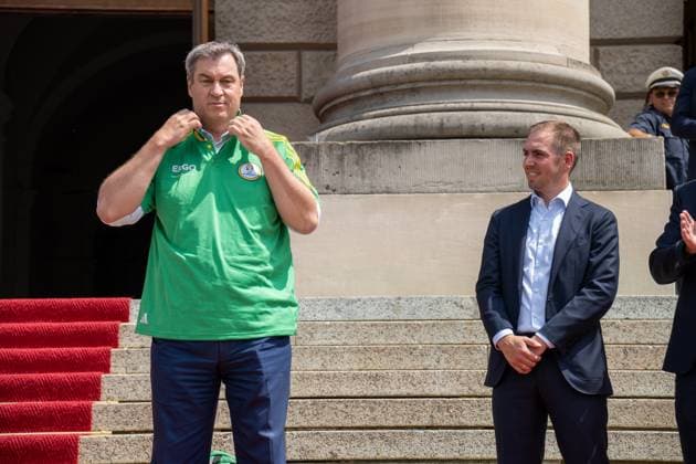 Munich, Bavaria, Germany - 11 July 2024: Prime Minister of Bavaria Dr. Markus Söder honoring the volunteers of the European Championship. He puts on a Volunteers jersey and stands next to tournament goalkeeper Philipp Lahm