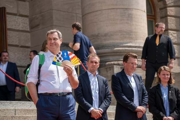 Munich, Bavaria, Germany: 11 July 2024: Dr. Markus Söder, Minister President of Bavaria, waves a UEFA fan because he is very hot. At the award ceremony for the volunteers of the UEFA Euro 2024 European Championship in Germany in Munich in the lower Hofgarten.