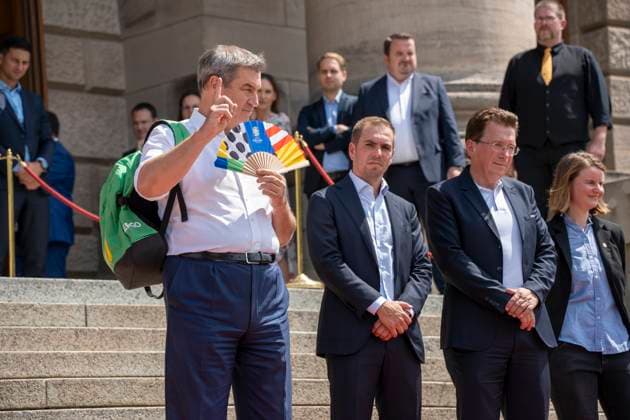 Munich, Bavaria, Germany: 11 July 2024: Dr. Markus Söder, Minister President of Bavaria, waves a UEFA fan because he is very hot. At the award ceremony for the volunteers of the UEFA Euro 2024 European Championship in Germany in Munich in the lower Hofgarten.
