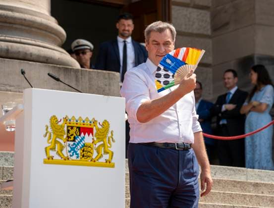 Munich, Bavaria, Germany: 11 July 2024: Dr. Markus Söder, Minister President of Bavaria, waves a UEFA fan because he is very hot. At the award ceremony for the volunteers of the UEFA Euro 2024 European Championship in Germany in Munich in the lower Hofgarten.