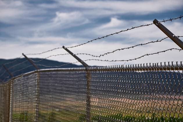 United States of America - June 9, 2024: Security fence and barbed wire in front of a rural landscape, symbolizing borders and restrictions
