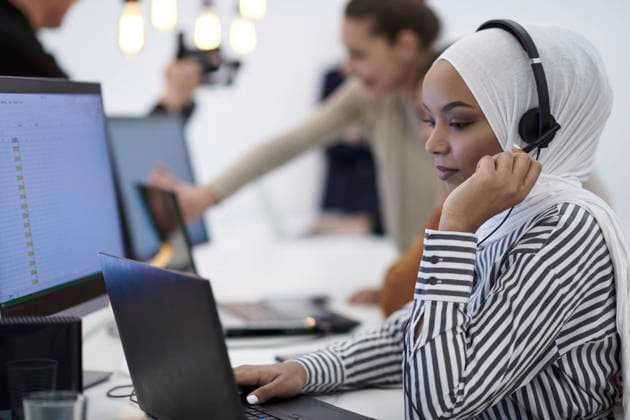 beautiful modern african Muslim businesswoman in office, wearing hijab speaking on headset at modern startup coworking space ,model released, Symbolfoto