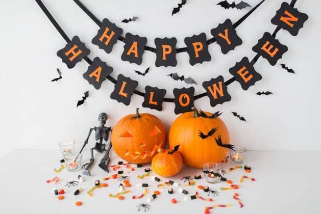 halloween, holidays and decoration concept - jack-o-lantern or carved pumpkins with candies and festive garland on white background. carved pumpkins with candies and halloween garland ,model released, Symbolfoto