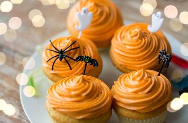 food, baking and holidays concept - cupcakes or muffins with halloween party decorations and candies on plate. halloween party decorated cupcakes on plate ,model released, Symbolfoto