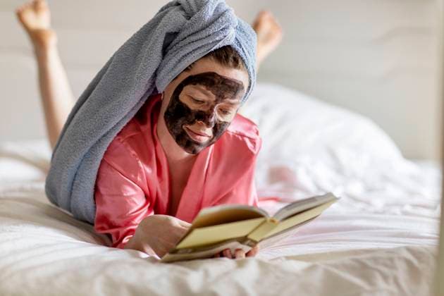 Woman with black face mask and towel on head reading book on bed London, England, United Kingdom R_THNZ240715-1484306-01 ,model released, Symbolfoto