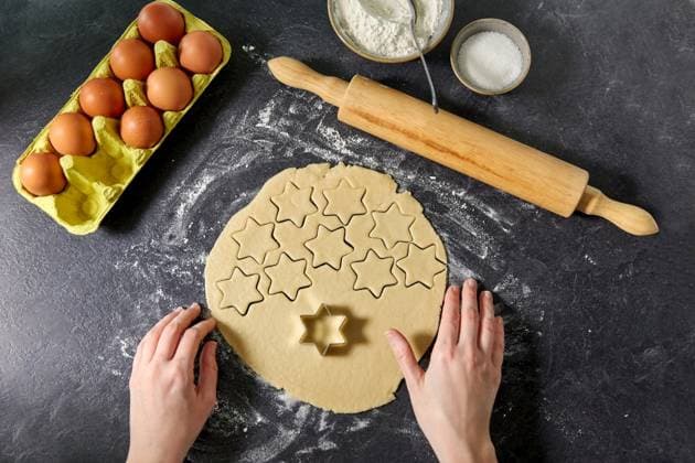 cooking food and culinary concept - hands, shortcrust pastry dough cut with star shaped cutter, rolling pin, eggs and flour on table. hands with shortcrust pastry dough and star mold ,model released, Symbolfoto