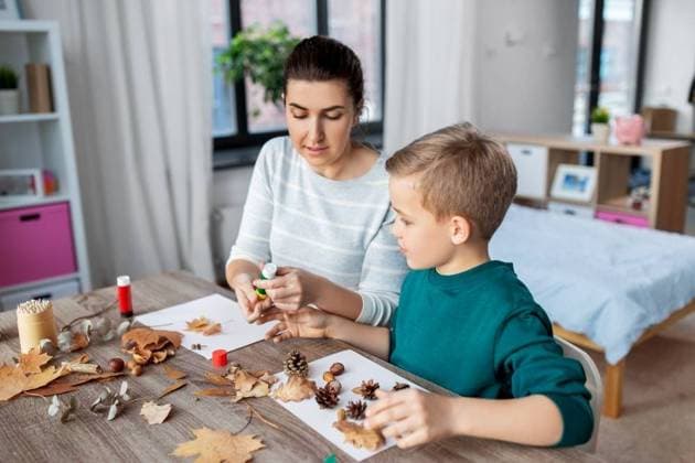 family, creativity and craft concept - mother and little son with glue sticks and paper making pictures of dry autumn leaves, pine cones and chestnuts at home. mother and son making pictures of autumn leaves ,model released, Symbolfoto