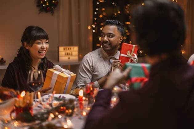 holidays, party and celebration concept - multiethnic group of happy friends having christmas dinner and opening presents at home. happy friends opening christmas presents at home ,model released, Symbolfoto