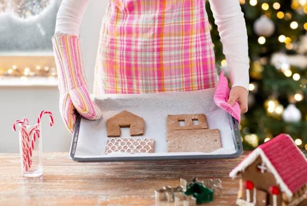 winter holidays, baking and food cooking concept - closeup of woman holding pan with gingerbread house details on it at home over christmas tree lights background. closeup of woman with gingerbread house on pan ,model released, Symbolfoto