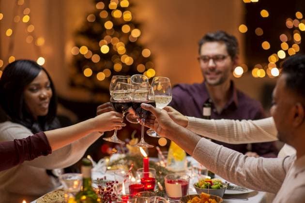 holidays, party and celebration concept - multiethnic group of happy friends having christmas dinner at home and drinking wine. happy friends drinking wine at christmas party ,model released, Symbolfoto