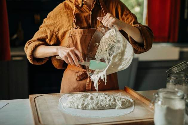 Hands of woman taking fermented dough out of glass bowl onto board in kitchen model released, Symbolfoto property released, VSNF02009