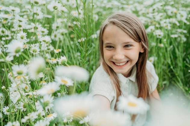 Creative Highlights Symbolfotos Happy girl looking at daisy flower in field model released, Symbolfoto, ANAF03282