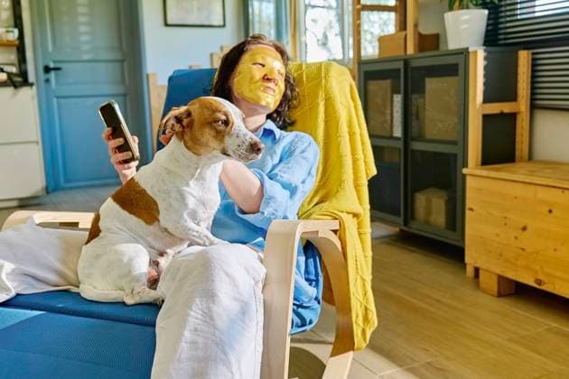 Woman wearing face mask and sitting on armchair with dog at home model released, Symbolfoto property released, CATF00033