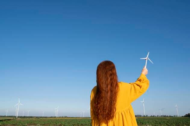 Creative Highlights Symbolfotos Teenage girl with red hair in a yellow dress holding a model of a wind generator on the background of a blue sky model released, Symbolfoto, VRAF00755