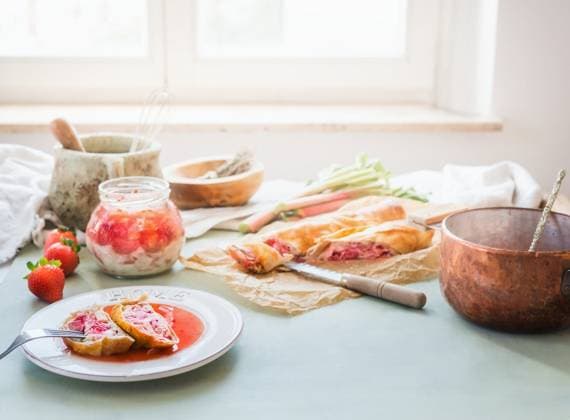 Delicious strawberry rhubarb strudel cake on sunny kitchen table with ingredients at window. Homemade seasonal cuisine ,model released, Symbolfoto