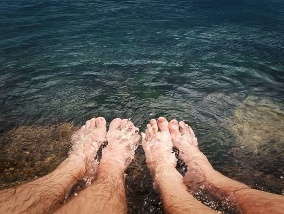Close up of two male legs in the clear sea water. Summer vacation, resting and relaxation concept ,model released, Symbolfoto