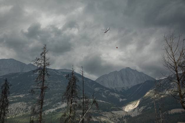 July 26, 2024, Jasper, Ab, CANADA: A helicopter buckets water onto smouldering fires outside of Jasper, Alta., on Friday July 26, 2024. Wildfires encroaching into the townsite of Jasper forced an evacuation of the national park and have destroyed over 300 of the town s approximately 1100 structures, mainly impacting residential areas. Jasper CANADA  - ZUMAc35_ 20240726_zaf_c35_235 Copyright: xAmberxBrackenx