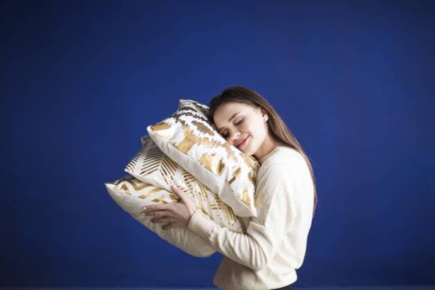Creative Highlights Symbolbilder Side view of smiling casual female with eyes closed cuddling cozy and trendy pillows with golden ornament against blue background Copyright: imageBROKER DaryaxPetrenko ibxiqx10540078.jpg ,model released, Symbolfoto ,property released