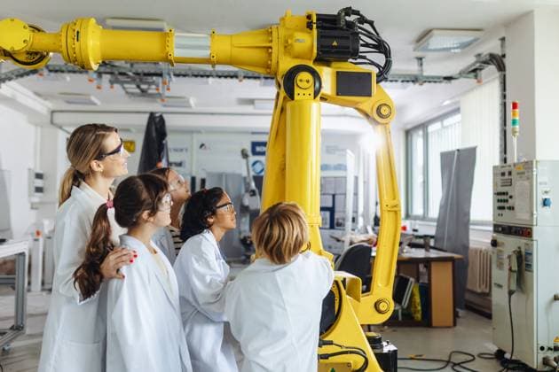 Field trip to real robotics laboratory, encouraging children in career in robotics. Real scientist talking with young students, showing them robotic arm. Field trip to real robotics laboratory, encouraging children in career in robotics. Real scientist talking with young students, showing them a robotic arm. model released