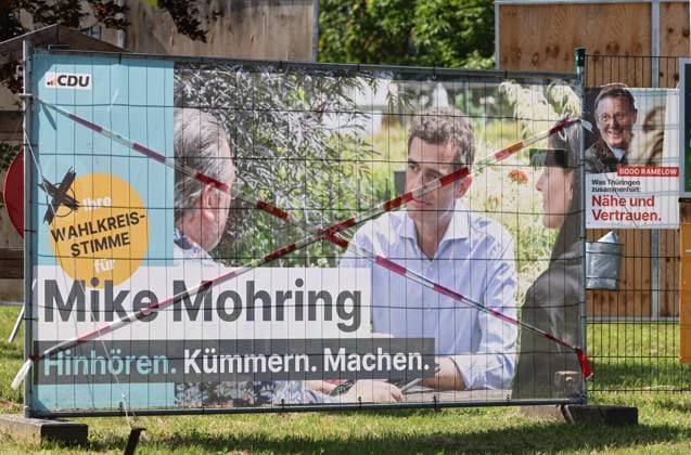 Wahlplakate 31.07.2024, Grossobringen, Wahlplakate zur Landtagswahl am 01.09.2024 in Thueringen im Bild: Transparent der CDU auf einem Bauzaun - Mike Mohring - Hinhoeren. Kuemmern. Machen. - das Plakat ist mit Absperrband durchkreuzt, rechts daneben ein Wahlplakat Die LINKE - Bodo Ramelow - Was Thueringen zusammenhaelt: Naehe und Vertrauen *** Election posters 31 07 2024, Grossobringen, election posters for the state election on 01 09 2024 in Thuringia in the picture banner of the CDU on a construction fence Mike Mohring Hinhoeren Kuemmern Machen the poster is crossed with barrier tape, right next to it an election poster Die LINKE Bodo Ramelow Was Thueringen zusammenhaelt Naehe und Vertrauen