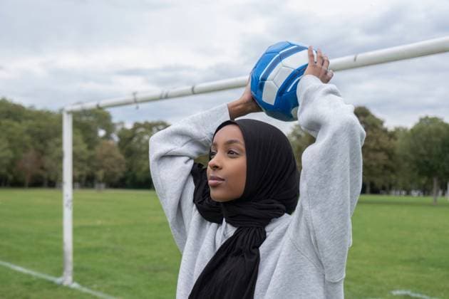 Smiling woman in hijab throwing soccer ball in park model released Copyright: xCulturaxCreativex