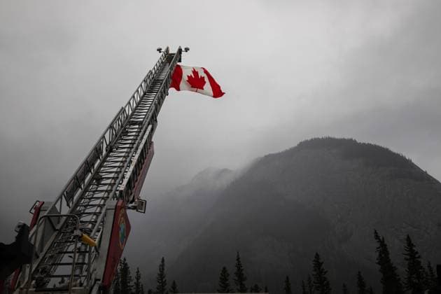 Kanada, Waldbrände in Alberta August 16, 2024, Jasper, Ab, CANADA: A Canadian flag hangs over the highway on on the first day residents are able to visit their properties in Jasper, Alberta on Friday August 16, 2024. Wildfire caused evacuations and widespread damage in the National Park and Jasper townsite. Jasper CANADA  - ZUMAc35_ 20240816_zaf_c35_048 Copyright: xAmberxBrackenx