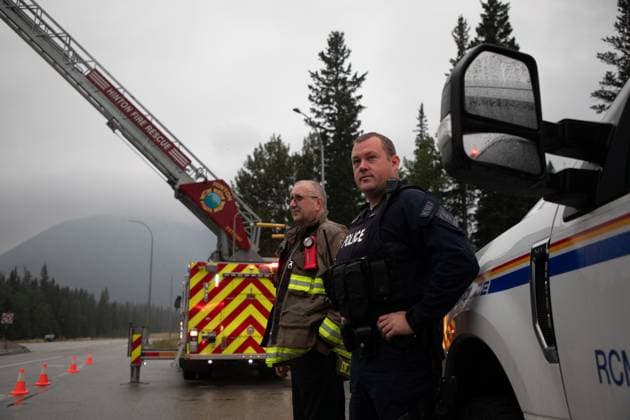 Kanada, Waldbrände in Alberta August 16, 2024, Jasper, Ab, CANADA: Hinton Fire Chief Mac de Beaudrap and an RCMP officer wait at the Park gate to greet returning residents to Jasper, Alberta on Friday August 16, 2024. Wildfire caused evacuations and widespread damage in the National Park and Jasper townsite. Jasper CANADA  - ZUMAc35_ 20240816_zaf_c35_052 Copyright: xAmberxBrackenx