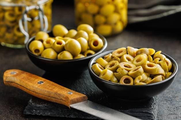 Sliced pickled green olives in brine in bowl on black table. Sliced pickled green olives in brine in bowl on a black table. Copyright: xZoonar.com JirixHERAx 22015723