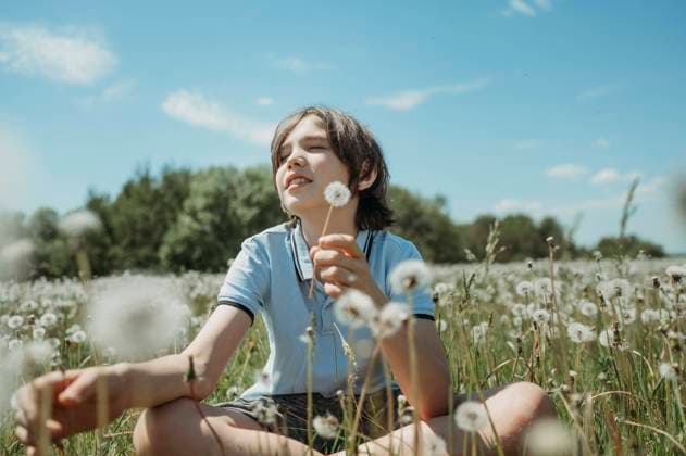 Creative Highlights Symbolbilder Boy holding dandelion flower and sitting in field under blue sky model released, Symbolfoto, ANAF03400