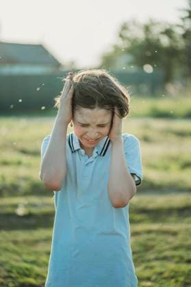 Frustrated boy covering ears standing at field model released, Symbolfoto, ANAF03425