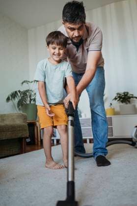 IMAGO Creative, Frühling, Frühjahrsputz Father and son cleaning carpet with vacuum cleaner at home model released, Symbolfoto property released, ANAF03465