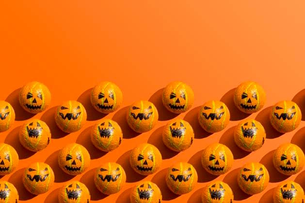 Pattern of rows of Halloween candy with jack o lantern wrapping against orange background, FLMF01123