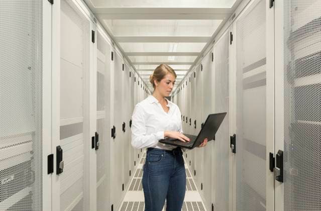 Engineer using laptop and standing in server room model released, Symbolfoto property released, MKJF01030