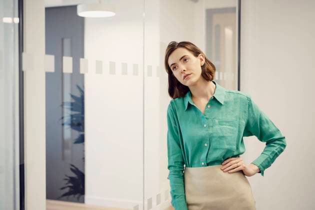 Tired businesswoman with hand on hip leaning on glass wall at office model released, Symbolfoto property released, PWF00863