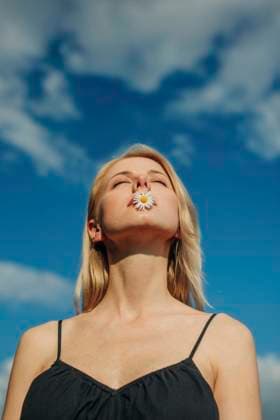 Creative Highlights Symbolbilder Beautiful woman with eyes closed holding daisy flower in mouth model released, Symbolfoto, VSNF02216