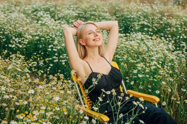 Creative Highlights Symbolbilder Smiling woman with hands behind head sitting on chair in meadow model released, Symbolfoto, VSNF02221