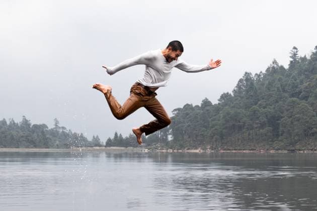 A man performs an energetic jump over a serene lake on a misty, rainy day, surrounded by tranquil forest and gentle raindrops, creating a sense of freedom and exhilaration Model Released EduardoGavira_ID23395_679858_011 Copyright: xEduardoxGavirax RECORD DATE NOT STATED