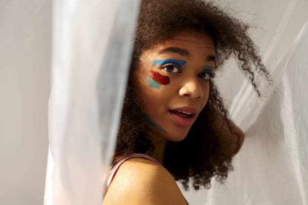 Creative Highlights Symbolbilder Schöne glückliche afrikanische amerikanische Ethnizität Frau mit kreativen Kunst Make up zur Seite schauen mit angenehmen Lächeln, fröhlich schwarz lockiges Mädchen mit Farbe Abstriche auf Gesicht posiert gegen graue Studio Hintergrund Beautiful happy african american ethnicity woman with creative art makeup looking aside with pleasant smile, cheerful black curly girl with color smears on face posing against gray studio background Copyright: imageBROKER DashaxPetrenko ibxiqx09198669.jpg ,model released, Symbolfoto ,property released