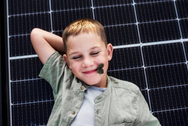 Creative Highlights Symbolbilder Top view of boy lying on roof with solar panels, looking at camera. Rooftop solar or photovoltaic system. Sustainable future for next generation. Top view of boy lying on roof with solar panels, looking at camera. Sustainable future for next generation concept. model released